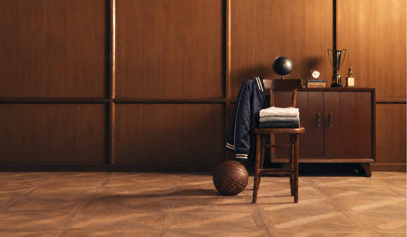 A wood-panelled clubroom: a navy varsity jacket and folded tees on a chair, a worn basketball on the floor, trophies on the cabinet.